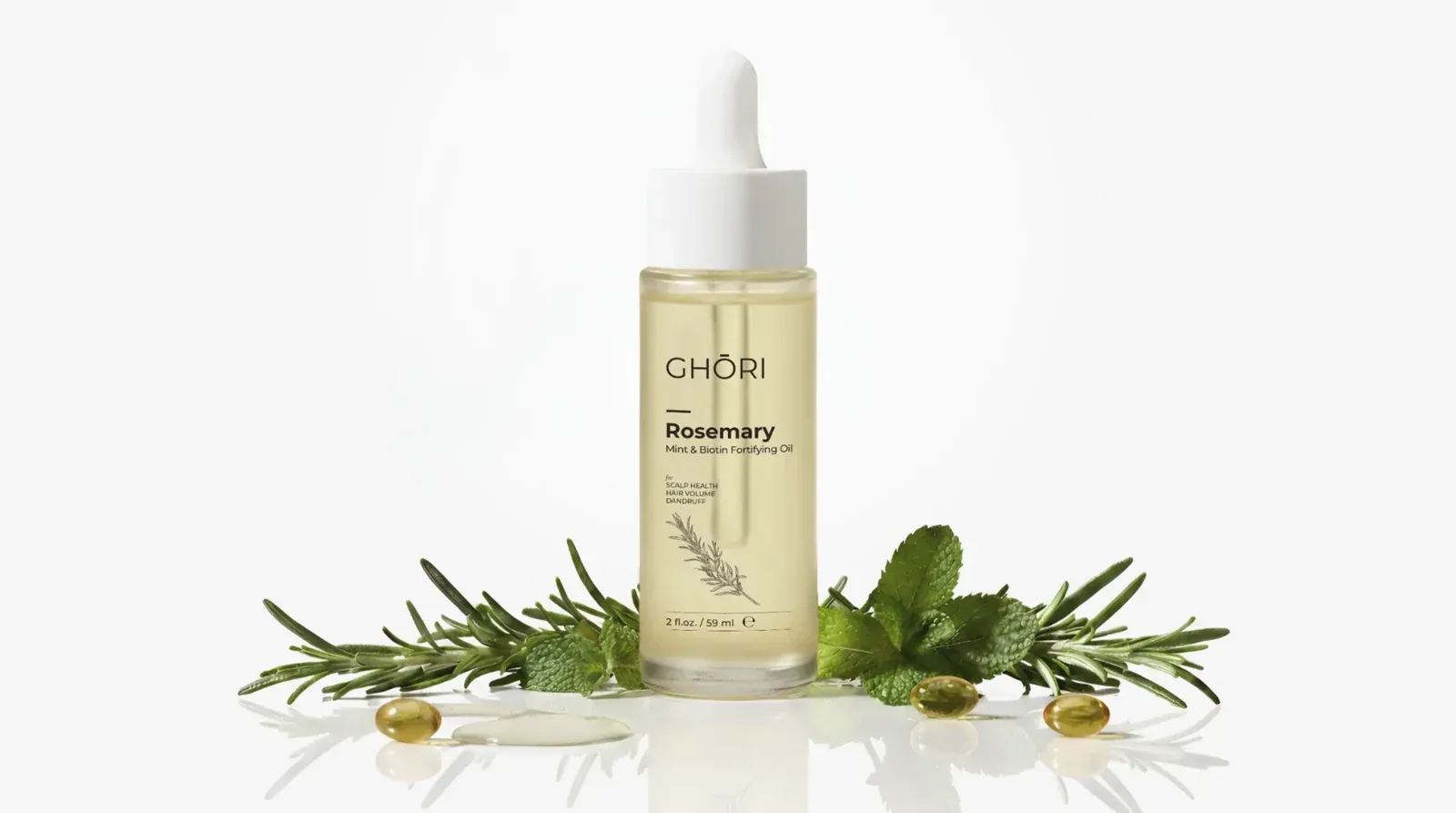 Ghori® Rosemary Mint & Biotin Oil bottle surrounded by fresh rosemary sprigs, mint leaves and golden biotin capsules